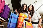 Beautiful happy twins holding present bags and smiling in fashion store