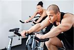 Young athletic couple spinning veloargometers in gym, male on focus