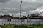 Rusty warehouse shack under moody sky. Street light emerging through the roof drying laundry by the window.