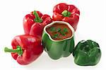 Three red bell peppers  and  a capsicum ragout in a green pepper ceramic ornament, isolated on white background
