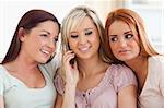 Smiling women sitting on a sofa with a mobile in a living room