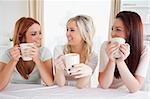 Women sitting at a table with cups in a kitchen