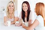 Charming young Women sitting at a table with cups in a kitchen