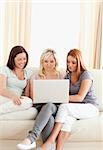 Laughing young women sitting on a sofa with a laptop in a living room