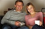 Couple With Coffee Mugs Watching Television