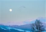 winter sunset mountain landscape with rime and snow covered forest and Moon on sky (Carpathian, Ukraine)