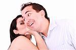 pretty girl talking secret to young man in his ear, man smiling over isolated white background