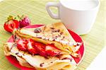 sweet pancakes with strawberry and cup of milk on white background