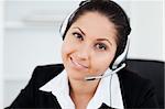 A cute smiling businesswoman with a headset in her office