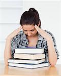 A frustrated young student is leaning on books