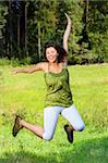 A picture of a pretty young woman jumping up high over natural green background