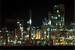 The converters, pipes, tubes chimneys and structures of a illuminated petrochemical plant at night