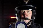 a police officer at night pointing his radar gun at traffic.