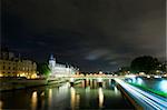 Bridges over the River Seine in Paris, with the Conciergerie on the Ile de la Cite nicely lit. A patch of clouds is lit with a lightbeam from below, just above the horizon