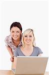 Portrait of smiling women with a laptop in a studio