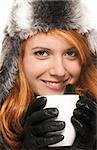 smiling young redhead woman in winter dress holding coffee cup  on white background