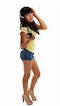 A pretty girl dressed in denim shorts and a yellow t-shirt is listening to music on a portable mp3 player.