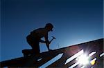 Builder or carpenter working on the roof - silhouette with strong back light