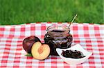 Jar of plum jam and some plums on the napkin