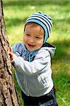 Portrait of a baby hiding behind a tree