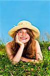 Young teenage girl laying in summer meadow resting chin on hand smelling flower