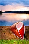 Canoe on beach at sunset on lake shore