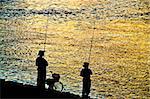 Fisherman silhouette on shoreline in sunset light