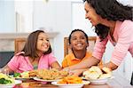 Mother Serving A Meal To Her Children At Home