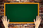 hand holding green blackboard on grunge wall