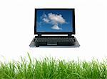 A laptop floating above green grass siolated against a white background