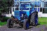 Painted in blue tractor standing before glass building