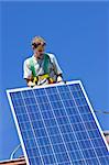 Man installing alternative energy photovoltaic solar panels on roof