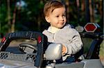 Close-up portrait of a serious baby in a toy car