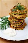 Zucchini fritters  with sour cream on a wooden table.