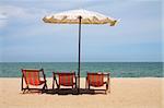 Deckchairs and parasol on the white sand beach facing cha-am beach, Thailand