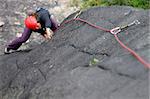 Young woman with helmet climbing basalt rock