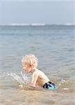 cheerful caucasian toddler splashing in the sea