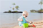 adorable toddler playing in sand on a tropical beach