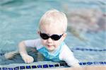 adorable toddler in sunglasses having fun in the pool