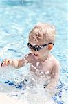 adorable toddler in sunglasses splashing in the pool