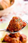 Close up of meat ball on a fork in front of the plate .