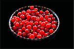 Bowl of red currant berries isolated on black background.