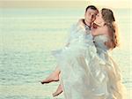 Groom holding up a his bride on the beach