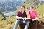 Male and female hikers in the German Alps near Oberstdorf reading a map for orientation.