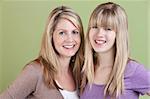 Happy Caucasian mother and daughter smile over green background