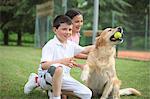Jeune garçon et une fille jouant avec une balle de Tennis Holding chien Labrador