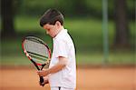 Boy Holding Tennis Racket And Looking Down