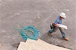 Carpenter walking at a construction site with building plans