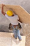 High angle view of a carpenter carrying a floor panel at a construction site