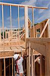 Hispanic carpenter taking a measurement of house framing